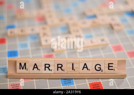 La parola francese 'matrimonio' (in inglese: "nozze") in legno piastrelle scrabble su un rack. Sullo sfondo di una scheda vintage, fuori fuoco con spazio di copia Foto Stock