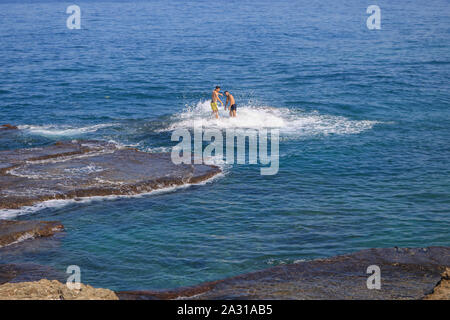 Gli uomini sono visto nuotare nel mare Mediterraneo in una giornata calda a Beirut con temperature sopra la media Foto Stock