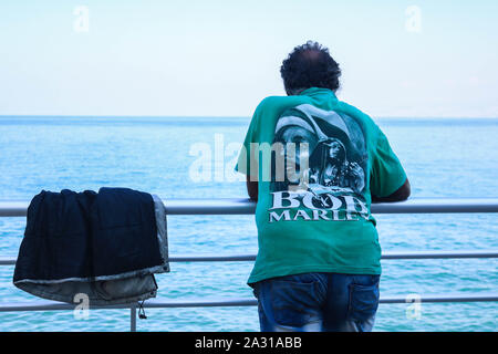 Un uomo che indossa un Bob Marley t-shirt appoggiata contro la balaustra sul lungomare di Beirut lungomare in una giornata calda a Beirut con temperature sopra la media Foto Stock