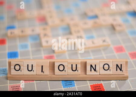 Le parole francesi "oui ou non" (in inglese: "sì o no") in legno piastrelle scrabble su un rack. Sullo sfondo di una scheda vintage, fuori fuoco, spazio di copia Foto Stock