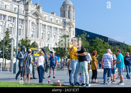 Statue in bronzo dei quattro Beatles in Liverpool, UK e una coppia gay che stanno prendendo i selfie con loro. Mostra la diversità tra i fan di banda. Foto Stock