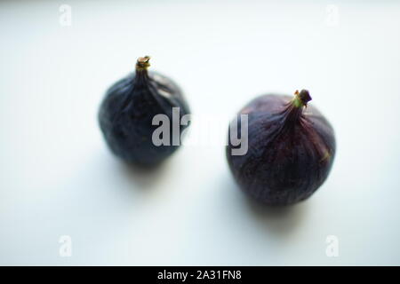 Due mature sweet fichi sul tavolo bianco. Selective soft focus. Sfocato Foto Stock