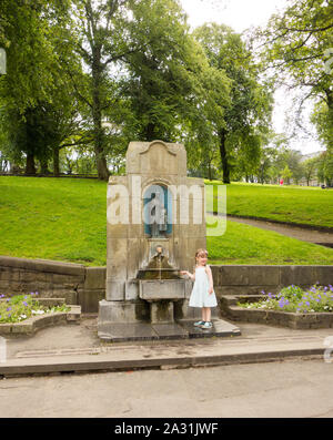 Giovane ragazza in piedi da Buxton acqua sorgiva presso il St Anne's bene nel Derbyshire cittadina termale di Buxton Inghilterra Foto Stock