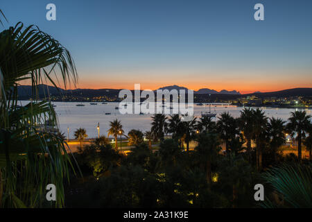 Vista panoramica del arancione tramonto sullo sfondo delle montagne e del mare che si affaccia sul lungomare Foto Stock