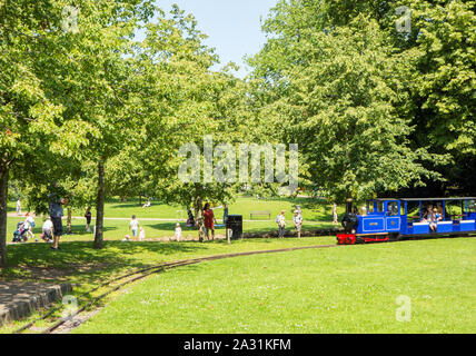 Persone e per vacanza in sella sulla miniatura convoglio ferroviario in Pavilion Gardens Buxton Derbyshire Inghilterra Foto Stock