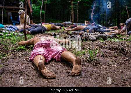 Le persone in cerca di illuminazione e guida spirituale sono visto che giace piatto su un suolo sacro in una radura del bosco a sciamanica e ritiro multiculturale. Foto Stock