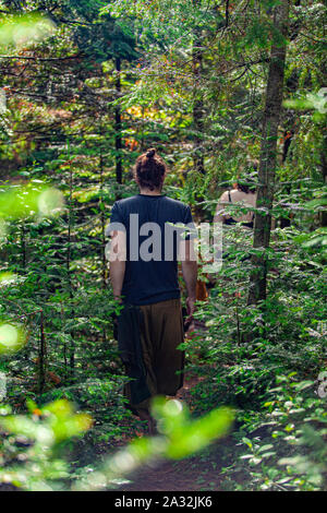 Un gruppo di persone che si vedono camminare attraverso il fitto bosco durante un sacro nudi escursione in cerca di consapevolezza e di illuminazione. Foto Stock