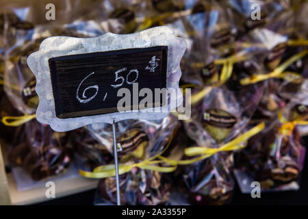 Un piccolo prezzo fatti a mano tag è visto da vicino in dettaglio su un mercato in stallo. Sfocata prodotti alimentari avvolte nel cellophane sono visti in background con copia spazio. Foto Stock