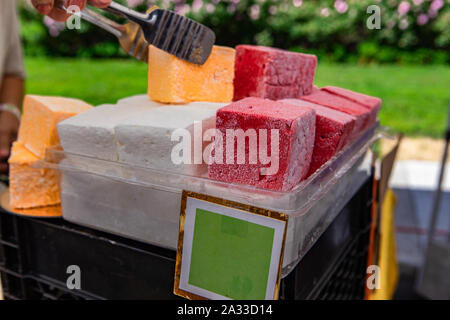 Colorati e pane appena sfornato dolci sono visto primo piano su un mercato display stand con un prezzo vuoto segno e spazio di copia durante una fiera per celebrare i produttori locali Foto Stock