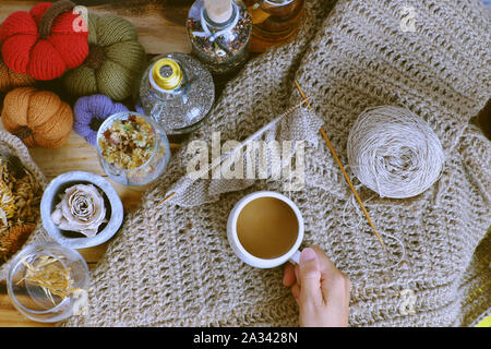 Top vista donna mano tenere tazza di caffè del mattino su sfondo autunno con decorazione stagionale tavolo ornamento per la casa decorazione come zucca, tela di piatto burlap Foto Stock