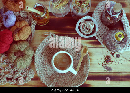 Top vista donna mano tenere tazza di caffè del mattino su sfondo autunno con decorazione stagionale tavolo ornamento per la casa decorazione come zucca, tela di piatto burlap Foto Stock