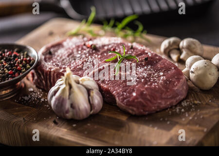 Costata di manzo sale pepe spezie l'aglio e i funghi. Materie di carni bovine su butcher board Foto Stock