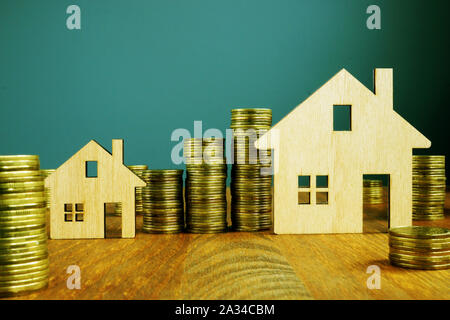 Investimenti immobiliari concetto. Case in legno e aumentando le colonne di denaro. Foto Stock