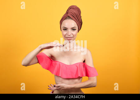 Ragazza giovane con asciugamano sulla sua testa isolata su sfondo arancione mostra le emozioni Foto Stock