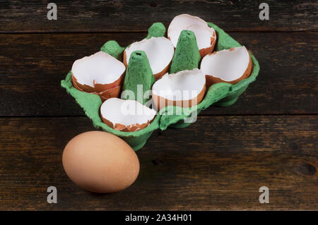 Studio shot di incrinate, pollo vuoti gusci delle uova in una scatola per uova al buio su un sfondo di legno - Giovanni Gollop Foto Stock