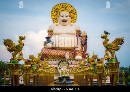 Sorridente gigante o felice statua del Buddha con cielo blu nel tempio buddista ( wat Plai Laem ), Koh Samui, Thailandia. Foto Stock