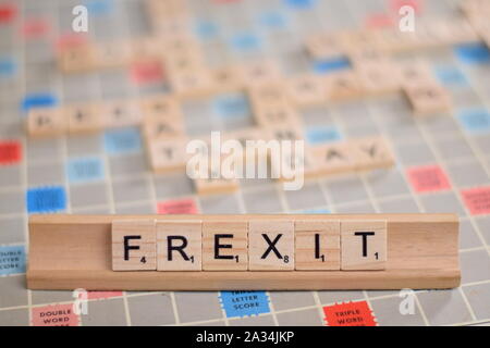 La parola "FREXIT' (francese possibile uscire dall'UE) in legno piastrelle scrabble su un rack. Lo sfondo è una scheda vintage, fuori fuoco con copia spazio. Foto Stock