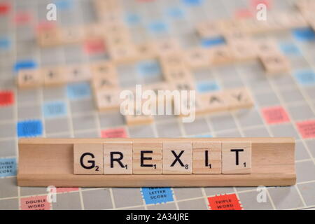 La parola "GREXIT' (Greco possibile uscire dall'UE) in legno piastrelle scrabble su un rack. Lo sfondo è una scheda vintage, fuori fuoco con copia spazio. Foto Stock