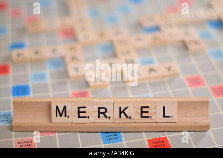 Il nome 'MERKEL' (Angela Merkel, Cancelliere della Germania) in legno piastrelle scrabble su un rack. Lo sfondo è una scheda vintage, fuori fuoco, copia dello spazio. Foto Stock