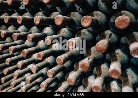 Le bottiglie di vino impilati nella vecchia cantina close-up sullo sfondo Foto Stock