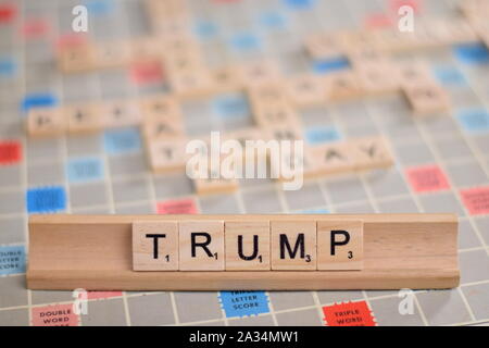 Il nome 'Trump' (Donald Trump, fake news, impeachment) in legno piastrelle scrabble su un rack. Sullo sfondo di una scheda vintage, fuori fuoco con copia spazio. Foto Stock