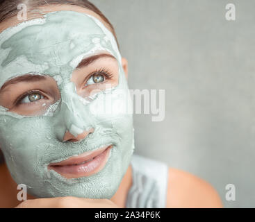 Ritratto di una bella ragazza facendo maschera facciale di argilla blu, home segreti del ringiovanimento del viso, foto con copia spazio, di bellezza e di cura della salute Foto Stock