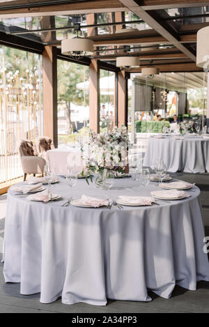 Lussuoso design di nozze per un matrimonio moderno. Tovaglia grigio nel pavimento sulla tavola rotonda e fiori in vaso Foto Stock