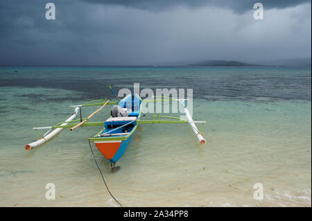 Canoa Outrigger sotto la pioggia tropicale tempesta, Gangga isola di Sulawesi, Indonesia. Foto Stock