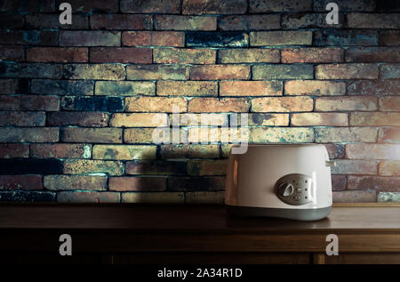 Tostapane bianco sulla credenza in legno in cucina con camera vintage muro di mattoni contro luce calda Foto Stock
