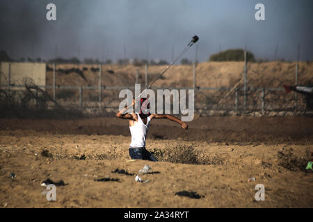 Un dimostrante palestinese utilizza un slingshot per scagliare pietre durante un anti-Israele dimostrazione per chiedere la fine di anni di assedio su Gaza sul confine Israel-Gaza nel sud GazaGaza striscia. Foto Stock