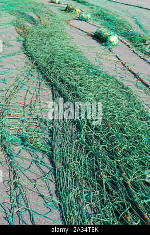 commercial fishing nets spread out on pier for repairs Foto Stock