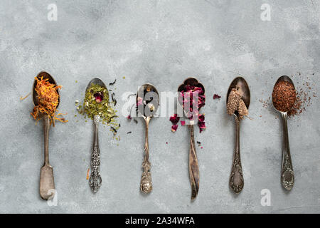 Diversi tipi di tè secco in cucchiai vintage. Lay piatto Foto Stock