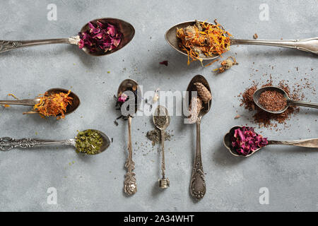 Diversi tipi di tè secco in cucchiai vintage. Lay piatto Foto Stock