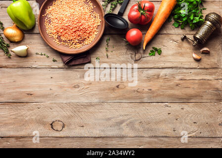 La cottura di sfondo con lenticchie rosse, stagionali verdure organiche sul tavolo di legno, vista dall'alto, copia dello spazio. Ingredienti per una sana stagionali di veg vegetariani Foto Stock