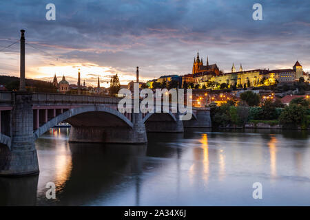 La notte scende al Ponte Manes oltre il fiume Moldava a Praga. Hradcany Castle in distanza. Foto Stock