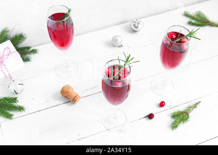 Natale mirtillo rosso mimosa con rosmarino su sfondo bianco, copia dello spazio. Cocktail con champagne per la mattina di Natale. Foto Stock