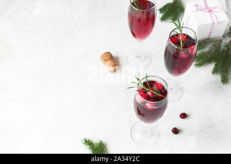 Cranberry mimosa con rosmarino e decorazioni di Natale su sfondo bianco, copia dello spazio. Cocktail con champagne per la mattina di Natale. Foto Stock