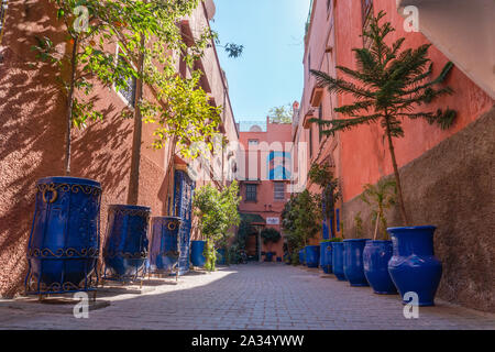 Pittoresca strada nella città di Marrakech con piante in vasi blu e dipinto di ciottoli Foto Stock