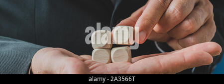 Imprenditore di impilamento vuoto quattro dadi di legno sul palm nella sua mano. Pronto per il tuo testo o simboli. Foto Stock