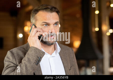 Grave barbuto broker in convenzionale chiamando uno dei client Foto Stock
