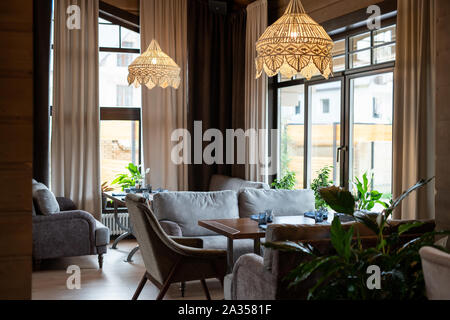 Parte del lussuoso ristorante con tavoli in legno e comodi divani Foto Stock