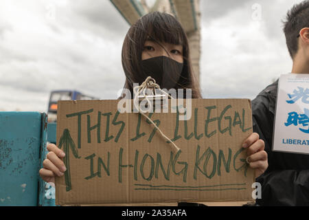 Londra, Regno Unito. 5 Ottobre, 2019. Artista cinese Badiucao sostenitori e unire le mani in una catena umana, una mostra di solidarietà con i dimostranti di Hong Kong. Il muro di Lennon bandiera, simboleggia la Hong Kongs lotta per la libertà è anche simbolicamente sollevata. Penelope Barritt/Alamy Live News Foto Stock