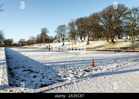 Un vicolo e un grande stagno vuoto coperto di neve all'ingresso Duthie park, Aberdeen, Scozia Foto Stock