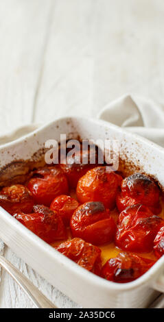 Arrosto di pomodori ciliegia in una piccola casseruola stretta fino Foto Stock