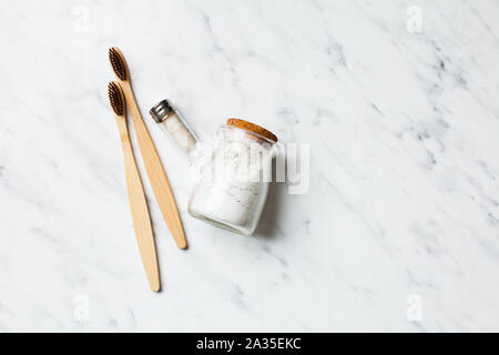 Close up di tre spazzolini da denti di bamboo e polvere di dente Foto Stock