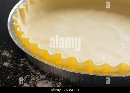 Base di torta in una forma di alluminio su di uno sfondo scuro vicino fino Foto Stock