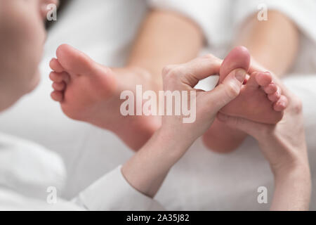 Professional masseur femmina dando riflessologia plantare per il piede della donna Foto Stock