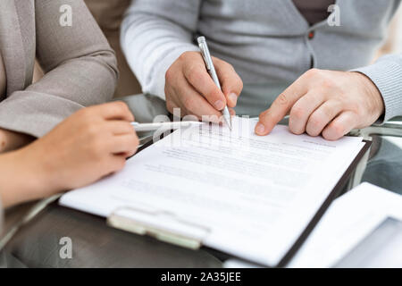 Uomo maturo con penna andando a firmare un contratto o altro documento finanziario Foto Stock