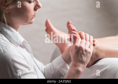 Professional masseur femmina dando riflessologia plantare per il piede della donna Foto Stock