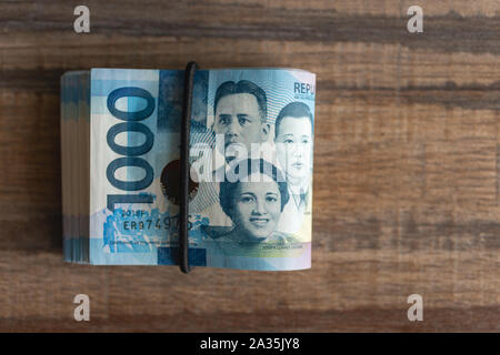 Bundle ripiegata di denaro in contanti di mille Filippine pesos. Corrompere, investimenti, pagare le bollette o ottenere lo stipendio. Foto Stock